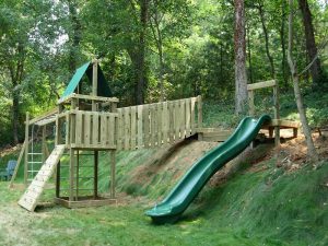 Playground uses the backyard hill for slide and suspension bridge linking the two decks - Asheville Playgrounds