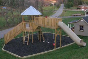 Play set with swing catwalk to the tube slide, a metal roof, and rubber mulched fall zone - Asheville Playgrounds