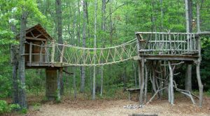 Rope bridge between two rustic decks built in the woods - Asheville Playgrounds