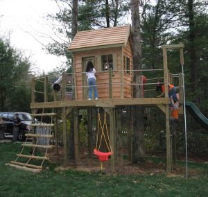 Whimsical cabin with tilted walls, slide, swing, and rope ladder - Asheville Playgrounds